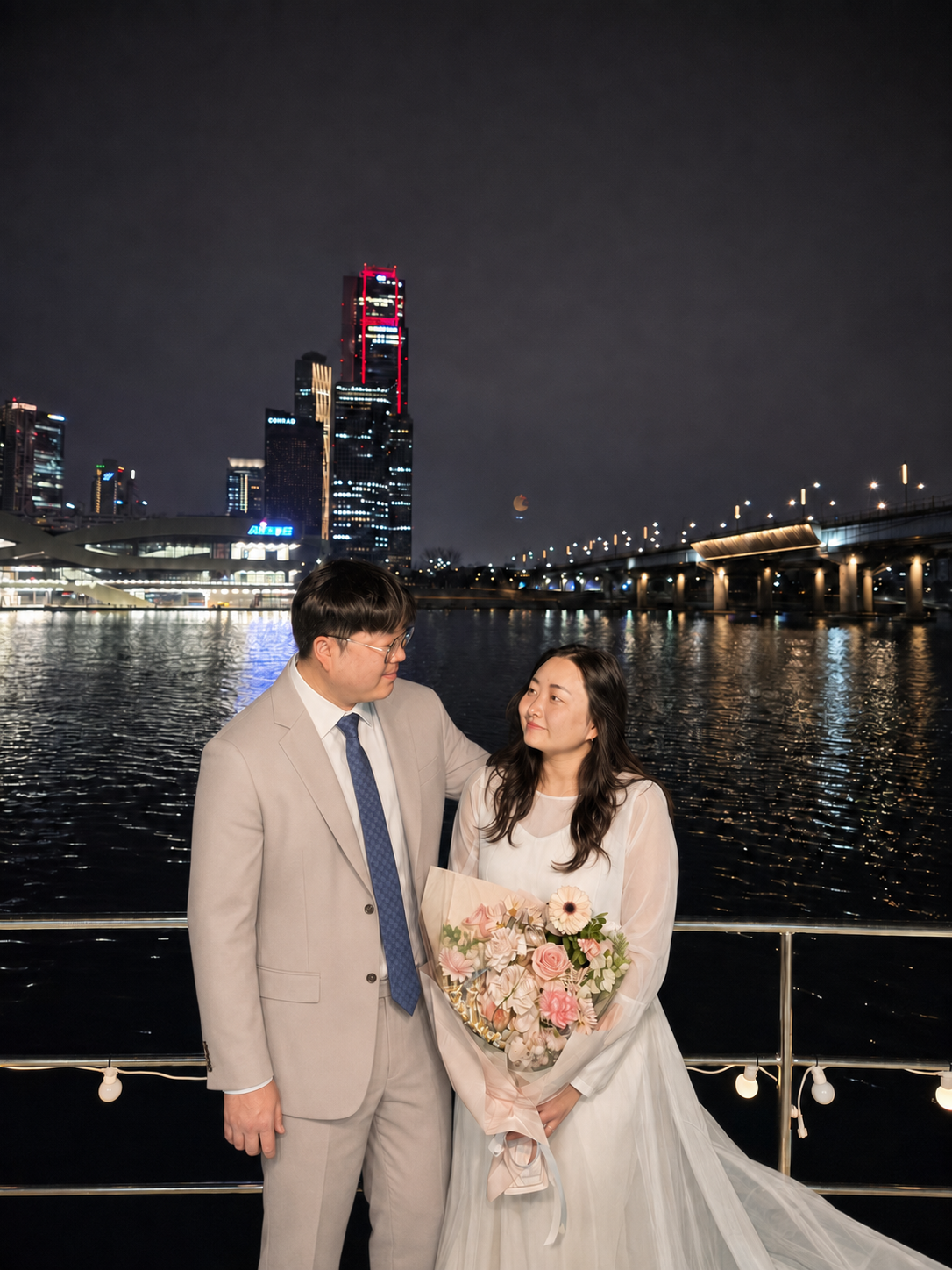 야경을 배경으로 순백색 웨딩드레스와 세미정장을 입고 서로 바라보는 송성은 김연재 커플